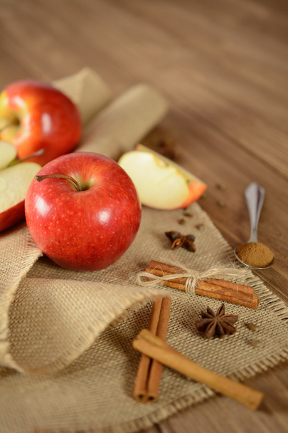 Apples and cinnamon on jute fabric and wooden background - Photo, Image