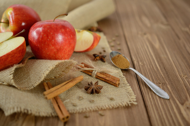 Apples and cinnamon on jute fabric and wooden background - Photo, image