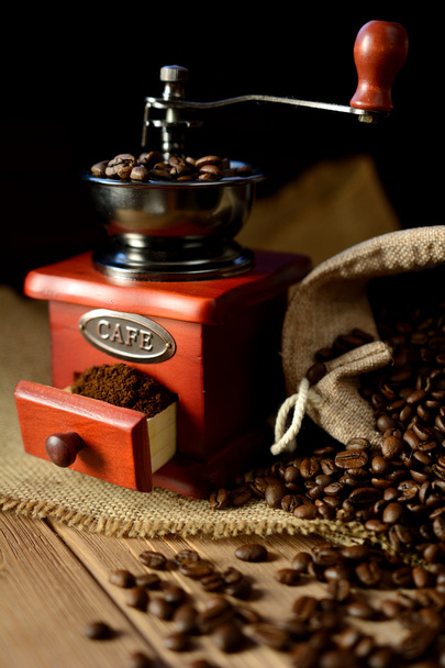 コーヒーミルと暗い背景の上のコーヒー豆 - 写真・画像