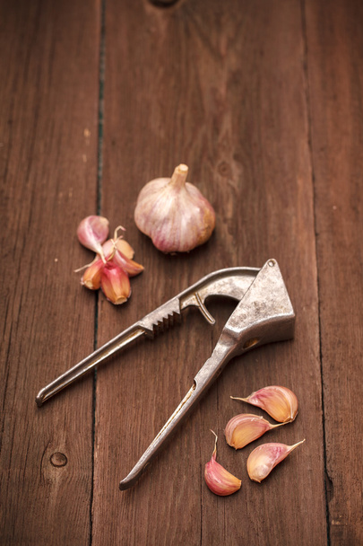 masher for garlic and garlic on a wooden background - Fotoğraf, Görsel