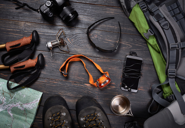 Hiking accessories set on dark wooden background:  boots, backpa - Foto, immagini