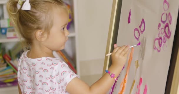 mała dziewczynka malarstwo w pokoju zabaw - Materiał filmowy, wideo
