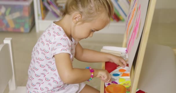 malá holčička míchání barev pro malování - Záběry, video