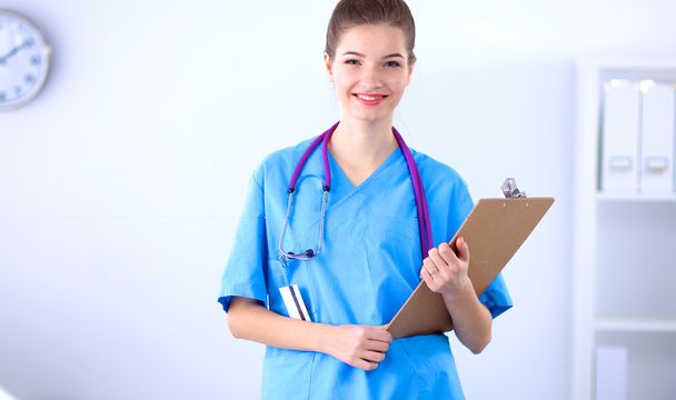 Smiling female doctor with a folder in uniform standing at hospital - Foto, imagen