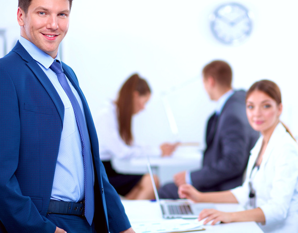 Успешный бизнесмен, стоящий со своим персоналом на заднем плане в офисе
 - Фото, изображение