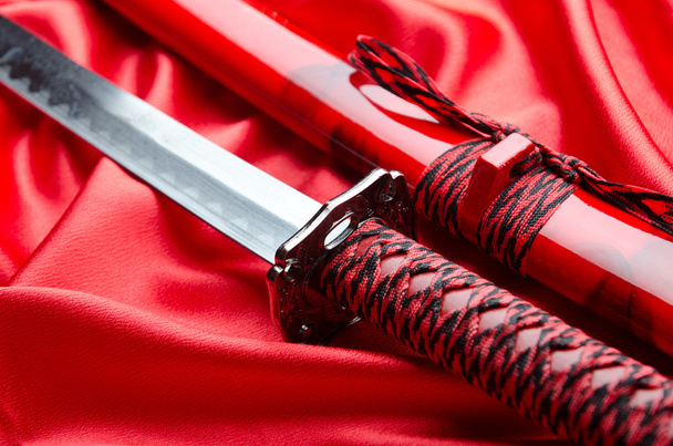 Japanese sword takana on red satin background - Fotografie, Obrázek