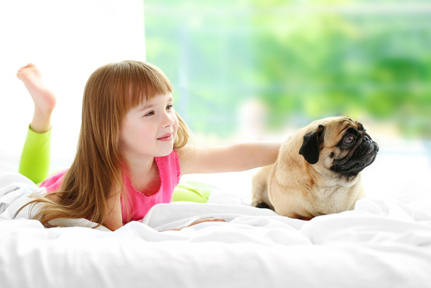Beautiful girl and cute pug on bed - Foto, imagen