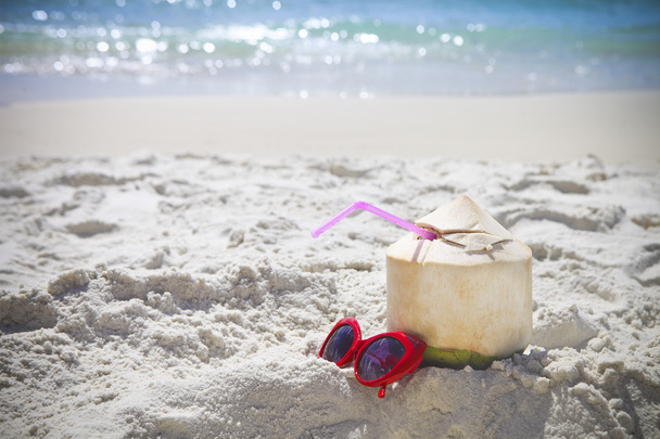 frischer Kokoscocktail und rote Sonnenbrille am Strand - Foto, Bild