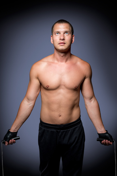 handsome athlete with a rope on a gray background - Foto, afbeelding