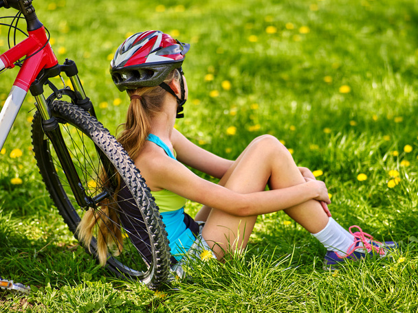Bicicletas ciclismo chica con casco sentado cerca de la bicicleta
. - Foto, imagen