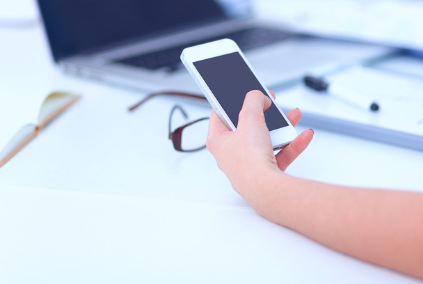 Businesswoman sending message with smartphone sitting in the office - Photo, image