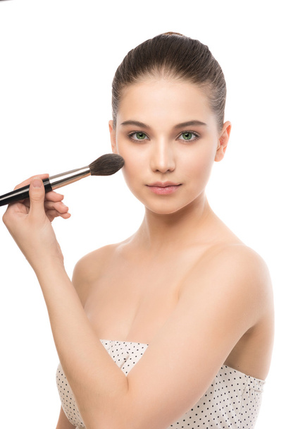 Young brunette woman with clean face. Girl perfect skin applying cosmetic brush. Isolated on a white. - Photo, image