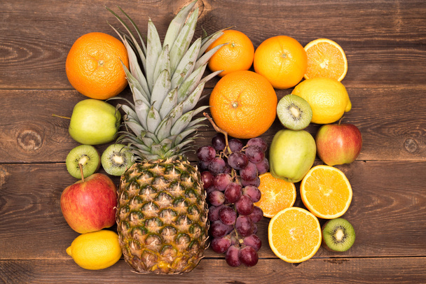 Tasty fruit background with orange, kiwi, grape, apples and lemon on the wooden table - Photo, Image