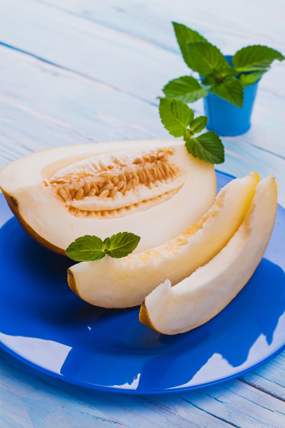 Fresh sweet melon in blue plate on the white wooden table - Foto, afbeelding