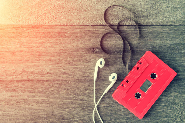 Rode cassettebandje met oortelefoon over houten tafel. bovenaanzicht. RET - Foto, afbeelding