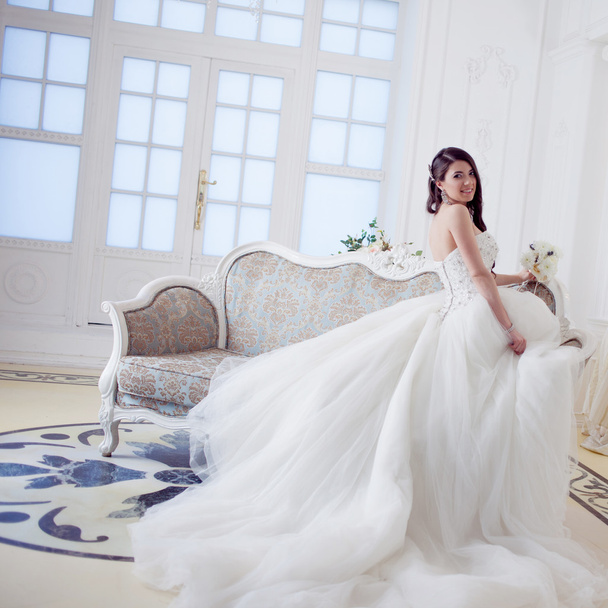 Portrait of beautiful laughing bride. Wedding dress with open back. Luxurious light interior - 写真・画像