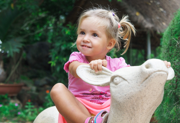 little girl rides a toy deer - Fotó, kép