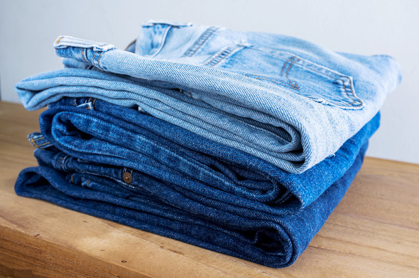 Pila di jeans blu su tavolo di legno
. - Foto, immagini