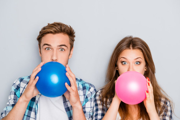 Portrait of happy young  man and woman inflating balloons - Photo, Image