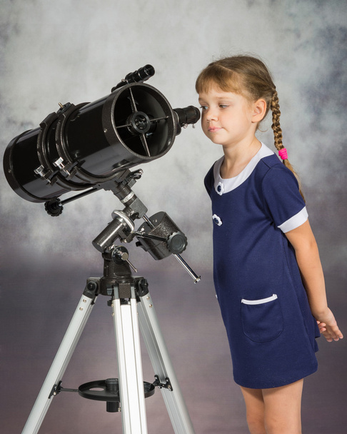 Любовница астрономии с интересом смотрит в окуляр телескопа
 - Фото, изображение