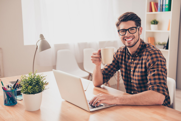 Happy smiling man in glasses working with laptop and drinking co - Фото, зображення