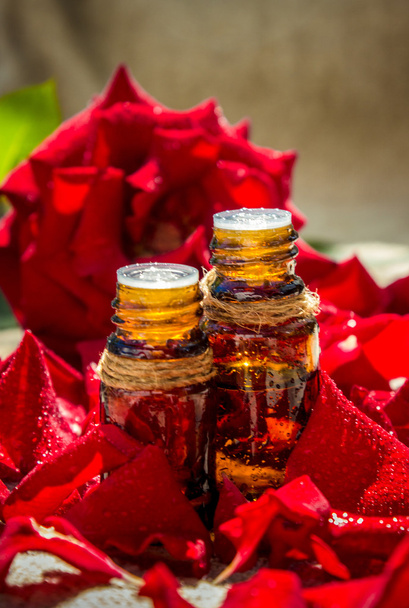 Эфирное масло розы в маленькой бутылке темного стекла
 - Фото, изображение