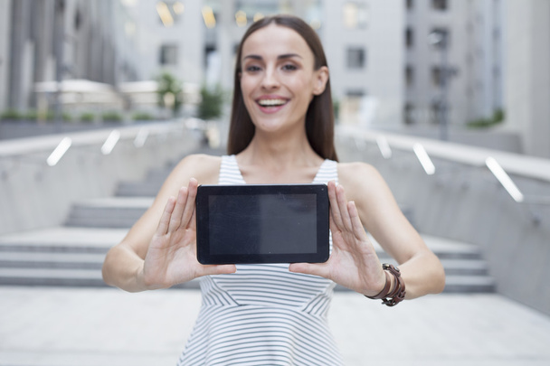 Beautiful girl laughing and holding a tablet. - Foto, afbeelding