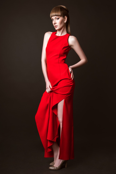 beautiful woman model posing in simple elegant red dress in the studio on black background - Φωτογραφία, εικόνα