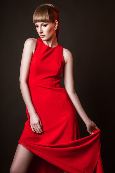 beautiful woman model posing in simple elegant red dress in the studio on black background - Photo, image