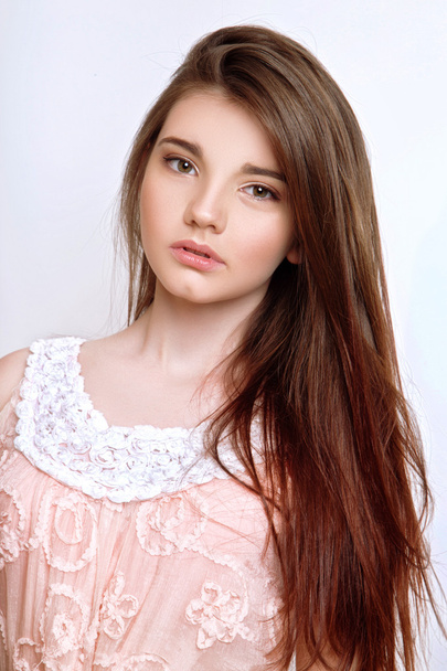 Piękna 13-letnia dziewczyna ubrana w różową sukienkę w studiu na białym tle - Zdjęcie, obraz
