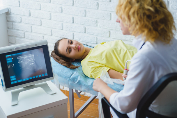 Female doctor examines girls hand with ultrasound in medical center - Valokuva, kuva