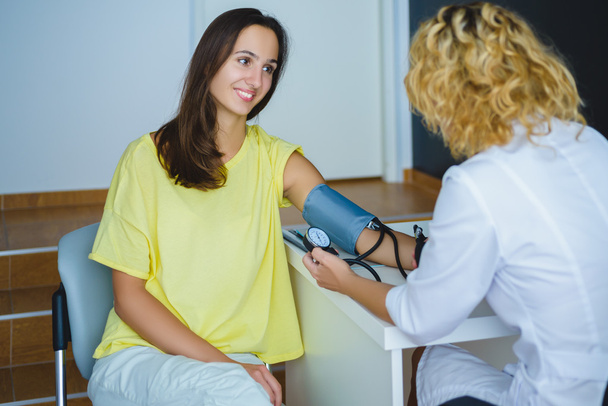 Naislääkäri tarkistaa nuoren naisen verenpaineen
 - Valokuva, kuva