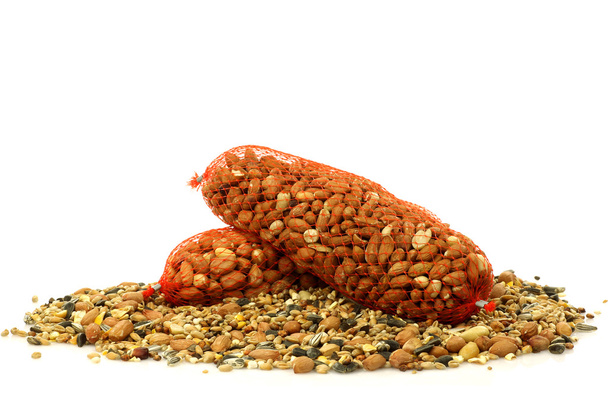 Haufen gemischtes Vogelfutter und Erdnüsse in Plastiknetzen - Foto, Bild