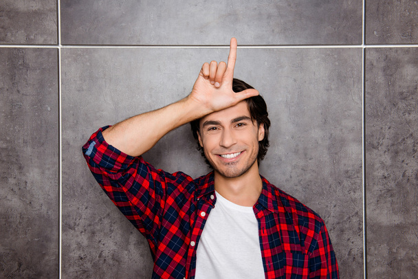 Funny young man showing sign loser with fingers near forehead an - Foto, Imagem