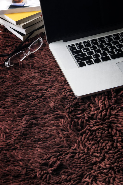 Laptop,eyeglasses  and books on brown carpet - Foto, Bild