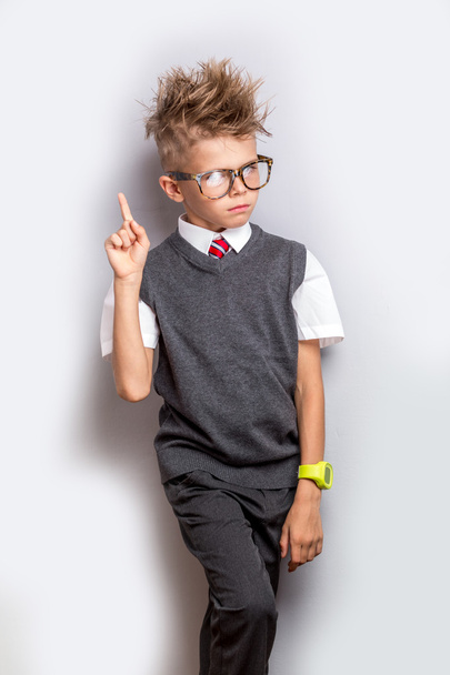 Cute schoolboy standing over grey background with finger up. Back to school concept - Photo, Image