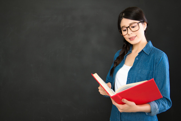 asia student reading her work standing in front of blackboard - Фото, зображення