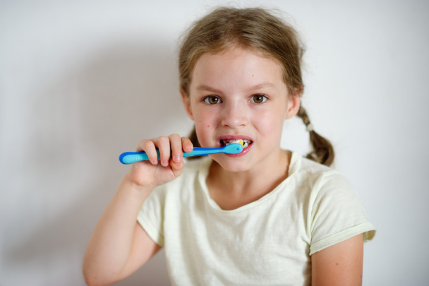 Pikkutyttö, jolla on saparot harjaamassa hampaitaan.
. - Valokuva, kuva