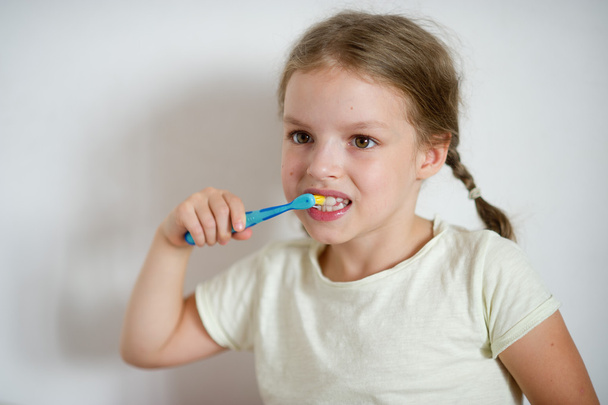 Petite fille mignonne avec des nattes se brossant les dents avec diligence
. - Photo, image