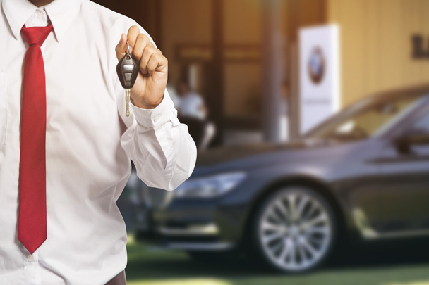 Prodavač aut předává klíče novému autu na pozadí - Fotografie, Obrázek
