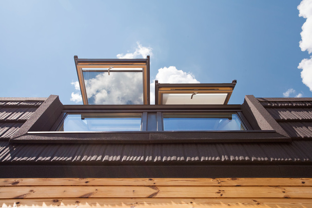 offene Dachfenster (Mansardenfenster) in Holzhaus mit Ziegel gegen blauen Himmel - Foto, Bild