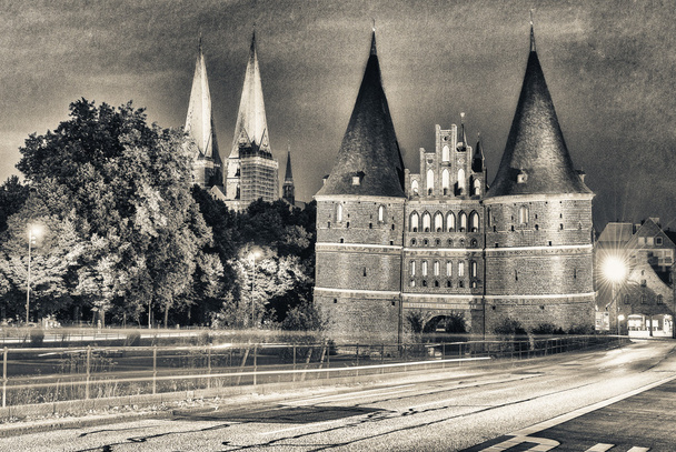 Lübeck, Německo. Středověké Holštýnské brány v noci s auto ligh - Fotografie, Obrázek