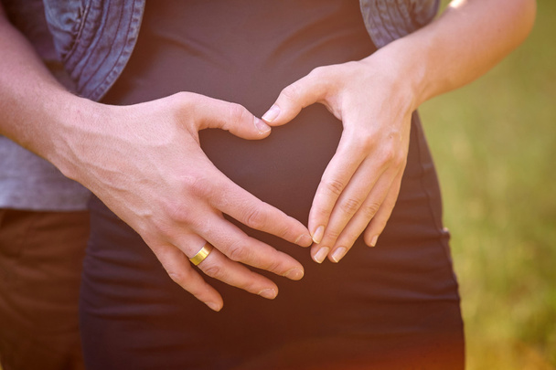 Těhotné bříško s prsty manžel srdce symbolu - Fotografie, Obrázek