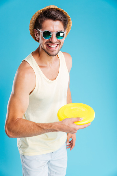 Smiling man in hat and sunglasses playing with frisbee disk - Photo, Image