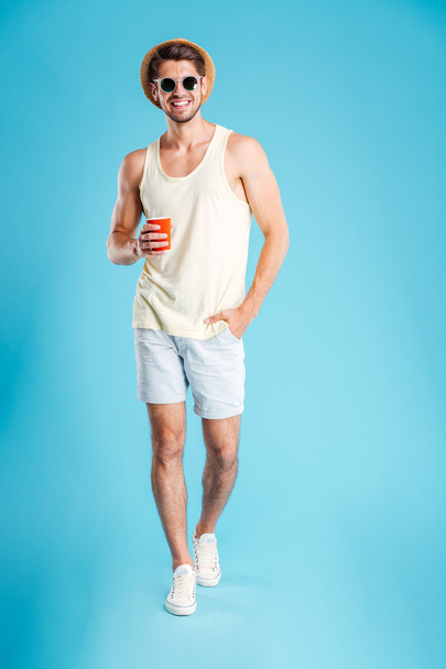 Full length of cheerful young man standing and drinking coffee - Photo, image