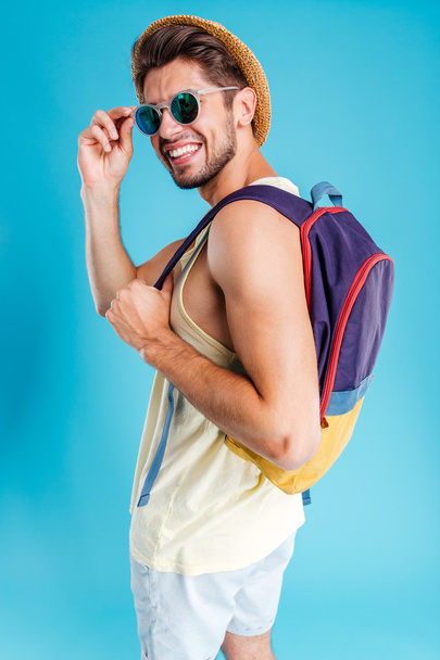 Smiling young man in hat and sunglasses with backpack - Фото, изображение