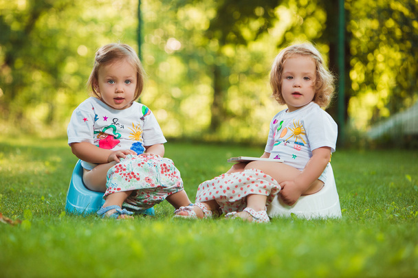 The two little baby girls sitting on pots - Valokuva, kuva