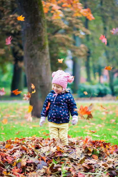 glückliches kleines Mädchen, das mit Blättern spielt - Foto, Bild