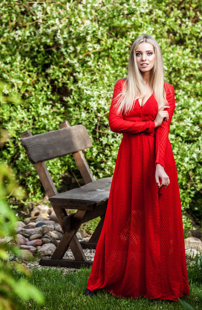 Outdoors portrait of beautiful young blond woman in long red dress - Фото, зображення