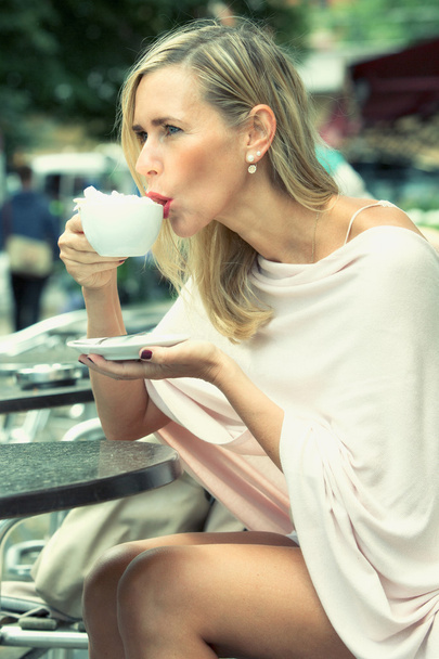カフェで外に座ってコーヒーを飲む女性 - 写真・画像
